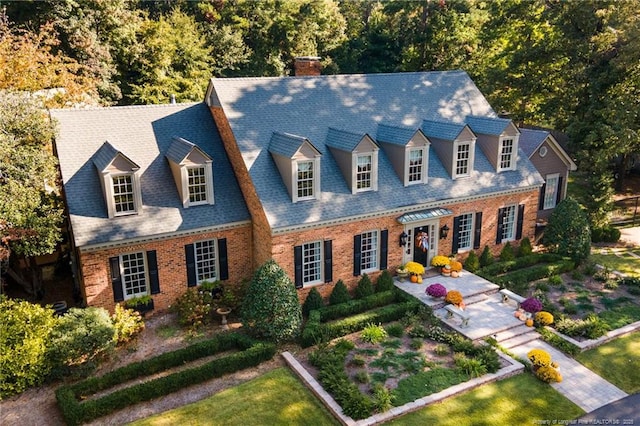 cape cod-style house featuring brick siding and a chimney