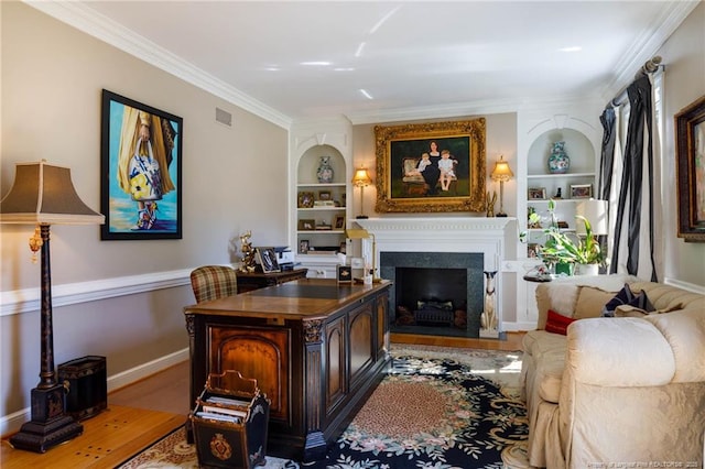 home office featuring a fireplace, crown molding, and built in shelves
