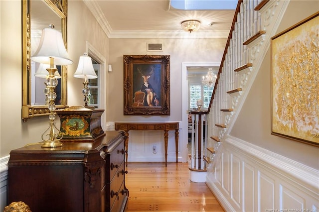 hall featuring light wood finished floors, stairs, visible vents, and crown molding
