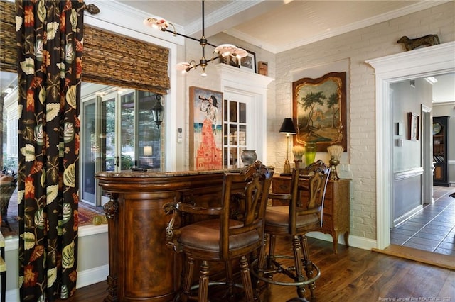 bar with dark wood-type flooring, brick wall, baseboards, a dry bar, and ornamental molding