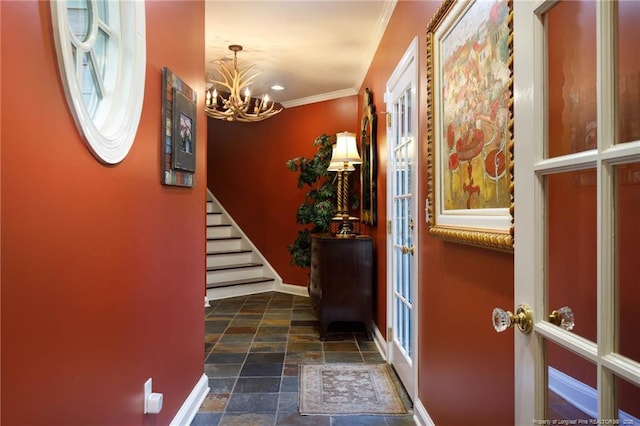 entryway with crown molding, stairway, stone finish floor, baseboards, and a notable chandelier