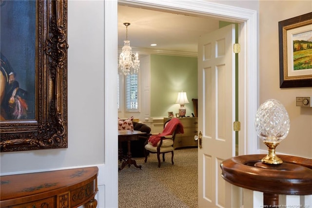 hall featuring carpet flooring, crown molding, and a notable chandelier