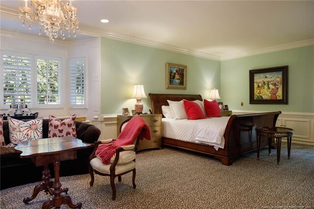 carpeted bedroom with an inviting chandelier, a wainscoted wall, a decorative wall, and crown molding
