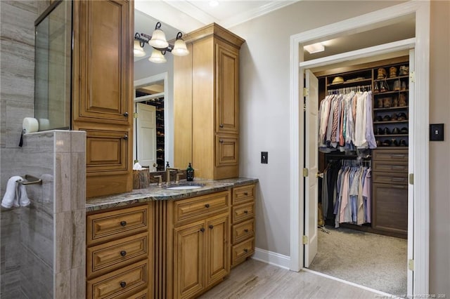 full bathroom featuring baseboards, tiled shower, vanity, and a walk in closet