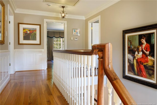 hall with hardwood / wood-style floors, an upstairs landing, a chandelier, and crown molding