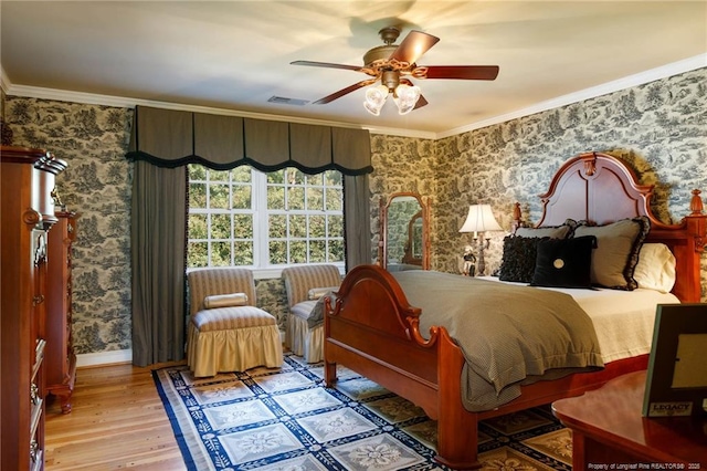 bedroom with wood finished floors, visible vents, wallpapered walls, ceiling fan, and ornamental molding