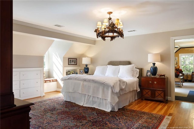 bedroom with visible vents, a chandelier, crown molding, and wood finished floors
