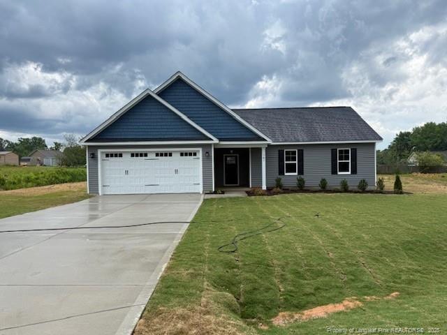 view of front of house featuring an attached garage, concrete driveway, and a front lawn