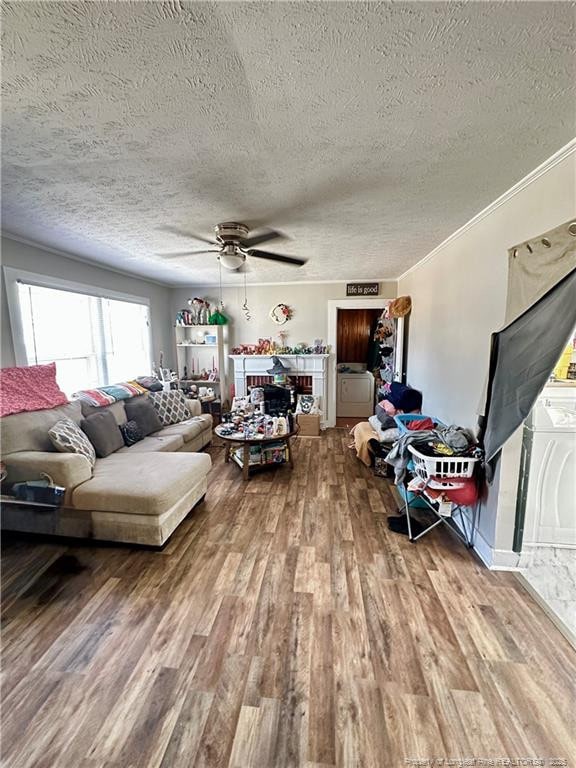living room with a textured ceiling, crown molding, ceiling fan, and wood finished floors