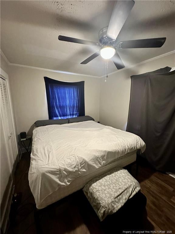 bedroom with a ceiling fan, ornamental molding, a closet, and wood finished floors
