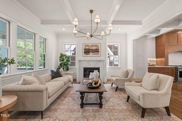 living room featuring an inviting chandelier, crown molding, light wood finished floors, and beam ceiling