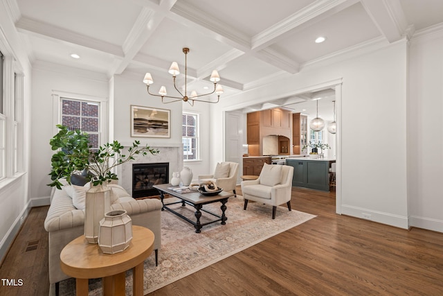 living area featuring an inviting chandelier, baseboards, beamed ceiling, and dark wood-type flooring