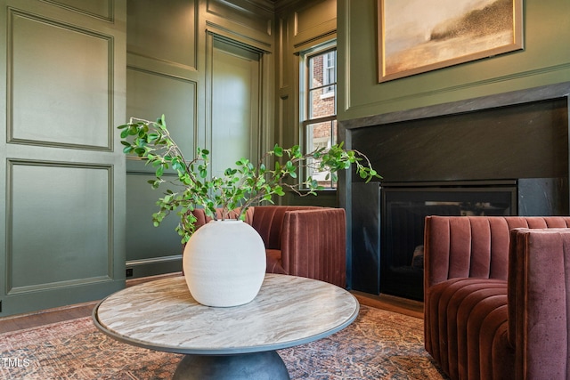 sitting room with a fireplace, a decorative wall, and wood finished floors