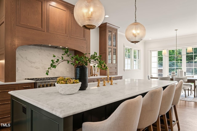 909 N Gregson St, Durham, NC 27701 - kitchen featuring hanging light fixtures, brown cabinetry, a center island with sink, and a kitchen bar