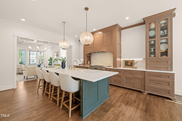 kitchen with recessed lighting, ornamental molding, an island with sink, and a kitchen bar