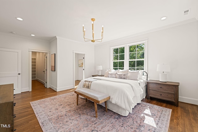 bedroom featuring visible vents, wood finished floors, baseboards, a chandelier, and ornamental molding
