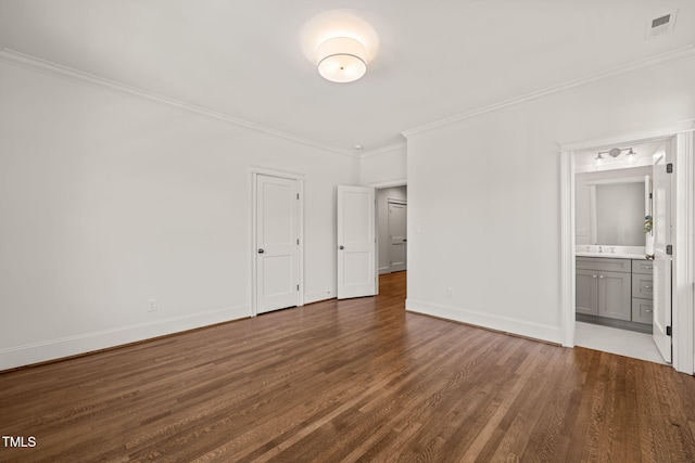 unfurnished bedroom with visible vents, ornamental molding, wood finished floors, baseboards, and ensuite bathroom