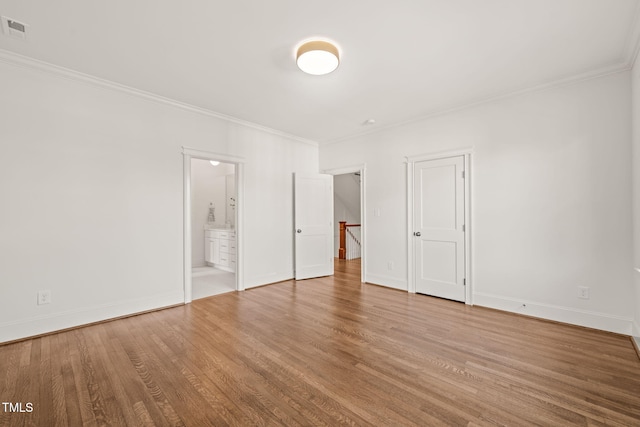 unfurnished bedroom featuring baseboards, visible vents, ornamental molding, and wood finished floors