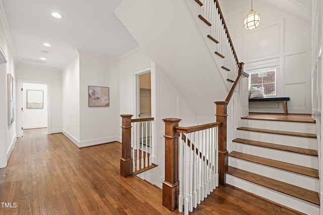 staircase with crown molding, visible vents, wood finished floors, baseboards, and recessed lighting