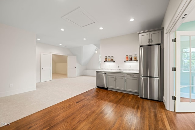 kitchen with appliances with stainless steel finishes, a sink, light countertops, gray cabinets, and dark wood-style floors
