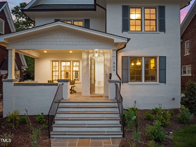 exterior space featuring covered porch and brick siding