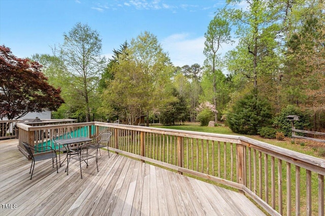wooden deck with outdoor dining area and a lawn