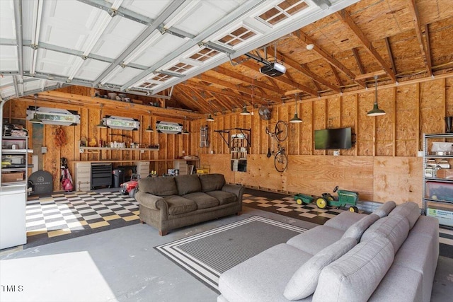 living room featuring concrete floors, a garage, and wooden walls