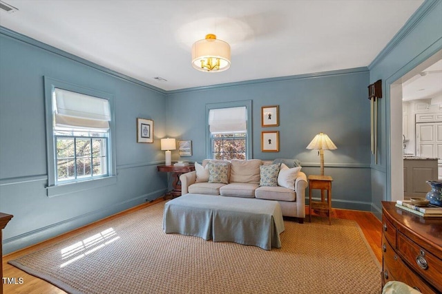 bedroom with wood finished floors, ornamental molding, baseboards, and multiple windows