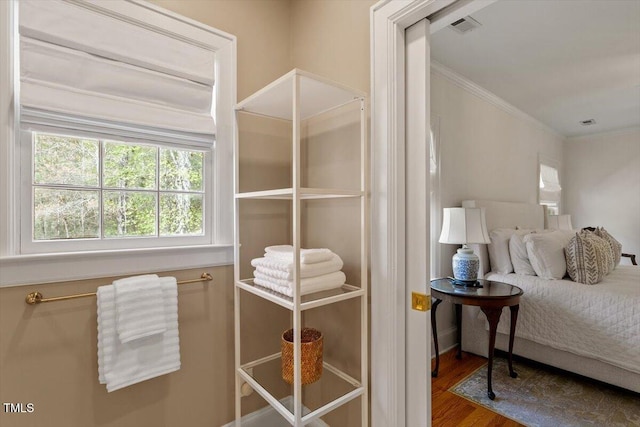 bedroom with visible vents, crown molding, and wood finished floors