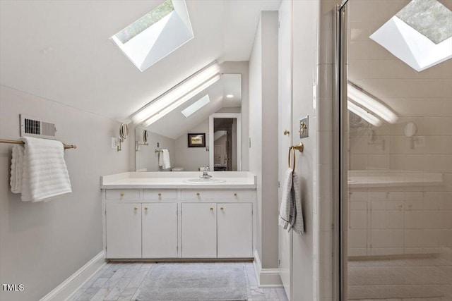 bathroom with vanity, baseboards, a stall shower, visible vents, and lofted ceiling with skylight