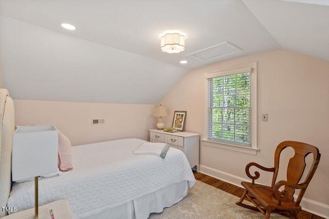 bedroom with lofted ceiling, baseboards, attic access, and wood finished floors
