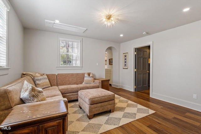 living room featuring recessed lighting, arched walkways, baseboards, and wood finished floors