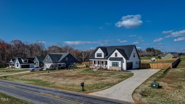 view of front facade featuring fence, an attached garage, concrete driveway, a front lawn, and a porch
