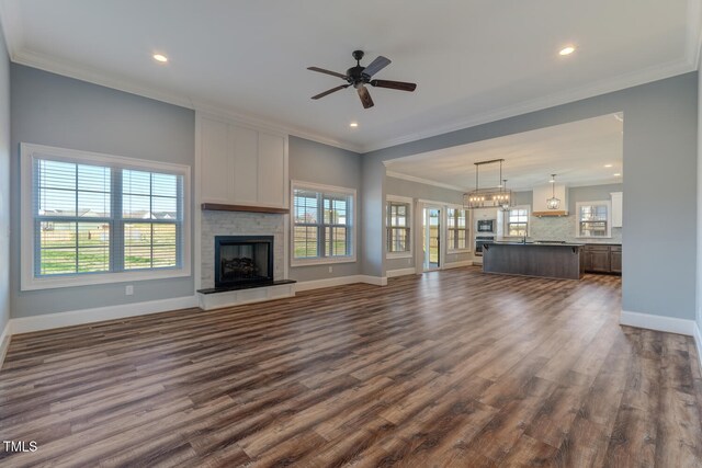 unfurnished living room featuring crown molding, a fireplace, baseboards, ceiling fan, and dark wood-style flooring