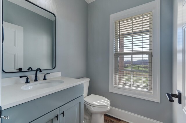 half bathroom with toilet, vanity, and baseboards