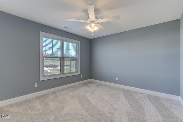 carpeted empty room with baseboards, visible vents, and a ceiling fan
