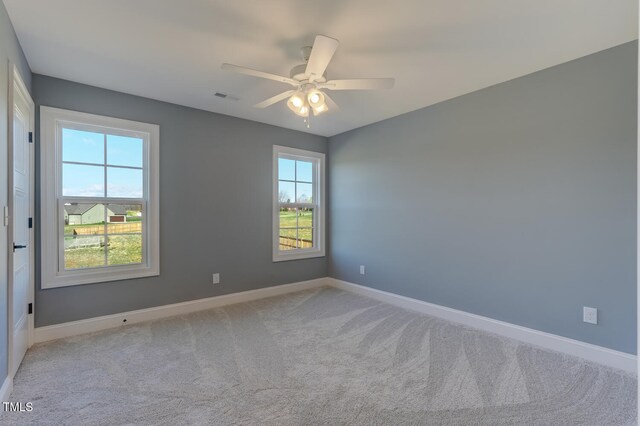 empty room featuring carpet flooring, a ceiling fan, baseboards, and visible vents