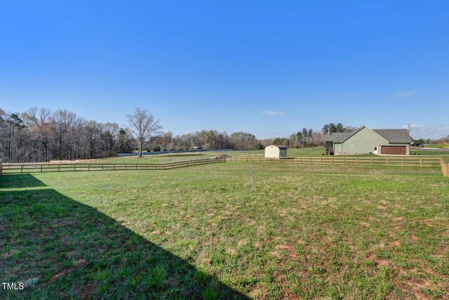 view of yard featuring an outdoor structure, fence, and a rural view