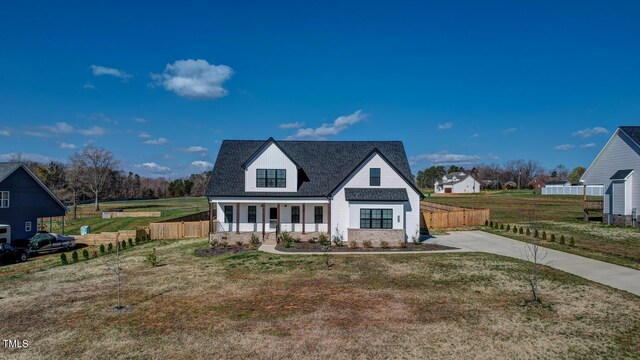view of front of property featuring driveway, fence, a front lawn, and a porch