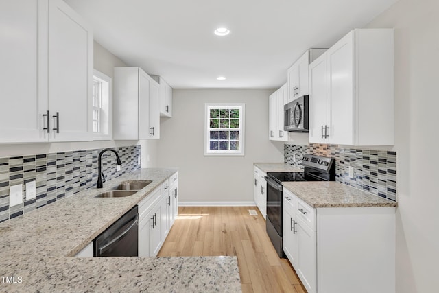 852 Fred Wilder Rd, Franklinton, NC 27525 - kitchen featuring appliances with stainless steel finishes, a sink, light stone counters, light wood-style floors, and white cabinets