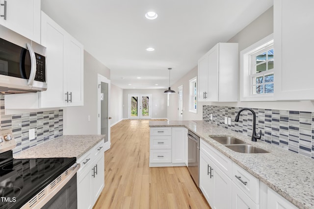 852 Fred Wilder Rd, Franklinton, NC 27525 - kitchen with appliances with stainless steel finishes, a sink, light wood-style flooring, white cabinetry, and decorative backsplash
