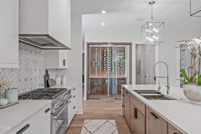 kitchen featuring light wood-type flooring, a sink, light countertops, high end stainless steel range, and custom exhaust hood