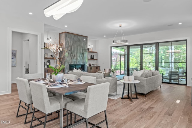 dining area with recessed lighting, a large fireplace, and light wood finished floors