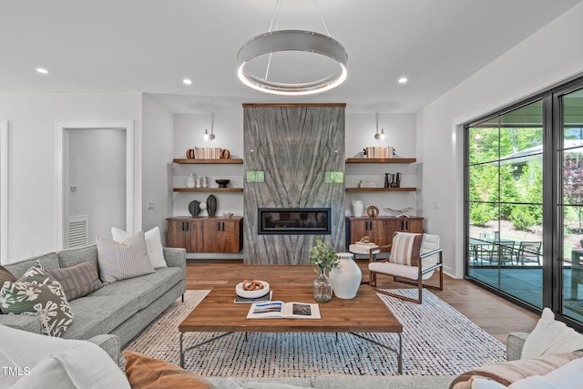 living room with visible vents, a high end fireplace, wood finished floors, and recessed lighting