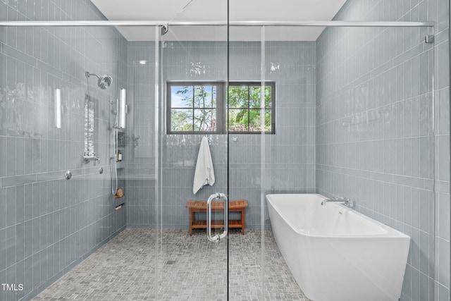 bathroom featuring tile walls, a freestanding bath, and a shower stall