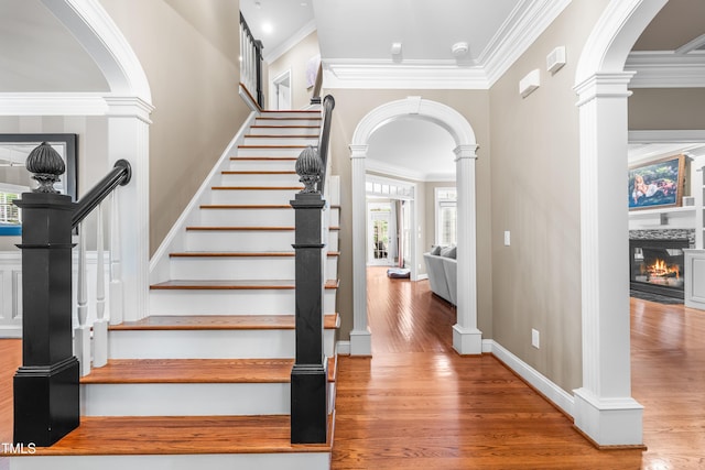 3821 Falls River Ave, Raleigh, NC 27614 - stairway with arched walkways, ornamental molding, a glass covered fireplace, wood finished floors, and ornate columns