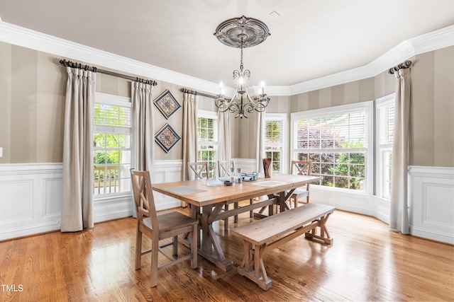 3821 Falls River Ave, Raleigh, NC 27614 - dining space with a chandelier, crown molding, a wainscoted wall, a decorative wall, and light wood finished floors