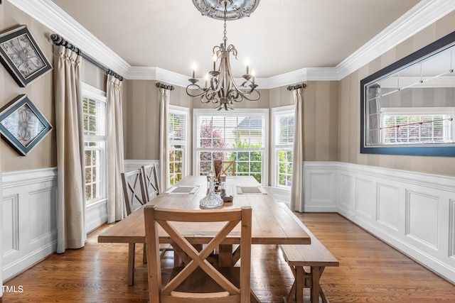 3821 Falls River Ave, Raleigh, NC 27614 - dining area with a chandelier, a decorative wall, light wood finished floors, wainscoting, and crown molding