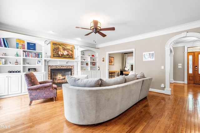 3821 Falls River Ave, Raleigh, NC 27614 - living area with crown molding, a ceiling fan, a fireplace, arched walkways, and light wood-type flooring
