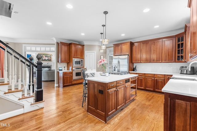 3821 Falls River Ave, Raleigh, NC 27614 - kitchen featuring appliances with stainless steel finishes, a kitchen island, ornamental molding, light wood-style flooring, and light countertops